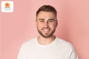 Ein Mann in einem weißen T-Shirt lächelt.