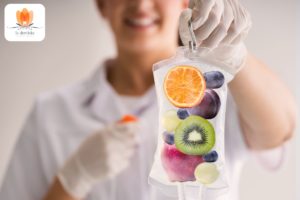 Eine Frau im weißen Laborkittel hält einen Infusionsbeutel mit Früchten.