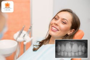 Eine Frau lächelt, während sie auf einem Zahnarztstuhl sitzt.