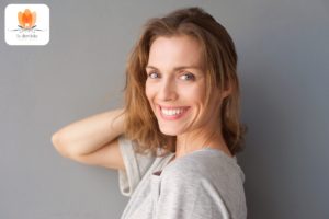 Eine lächelnde Frau mit den Händen auf den Schultern.