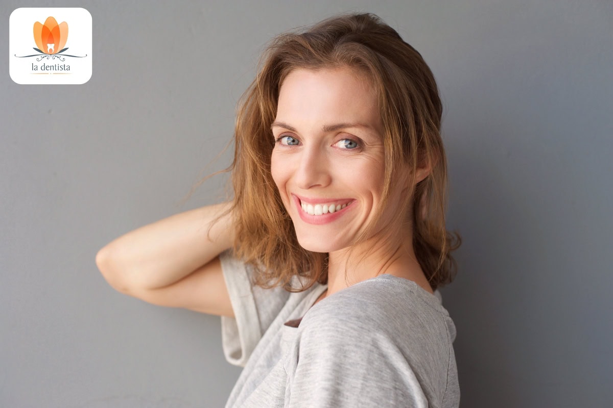 Eine lächelnde Frau mit den Händen auf den Schultern.